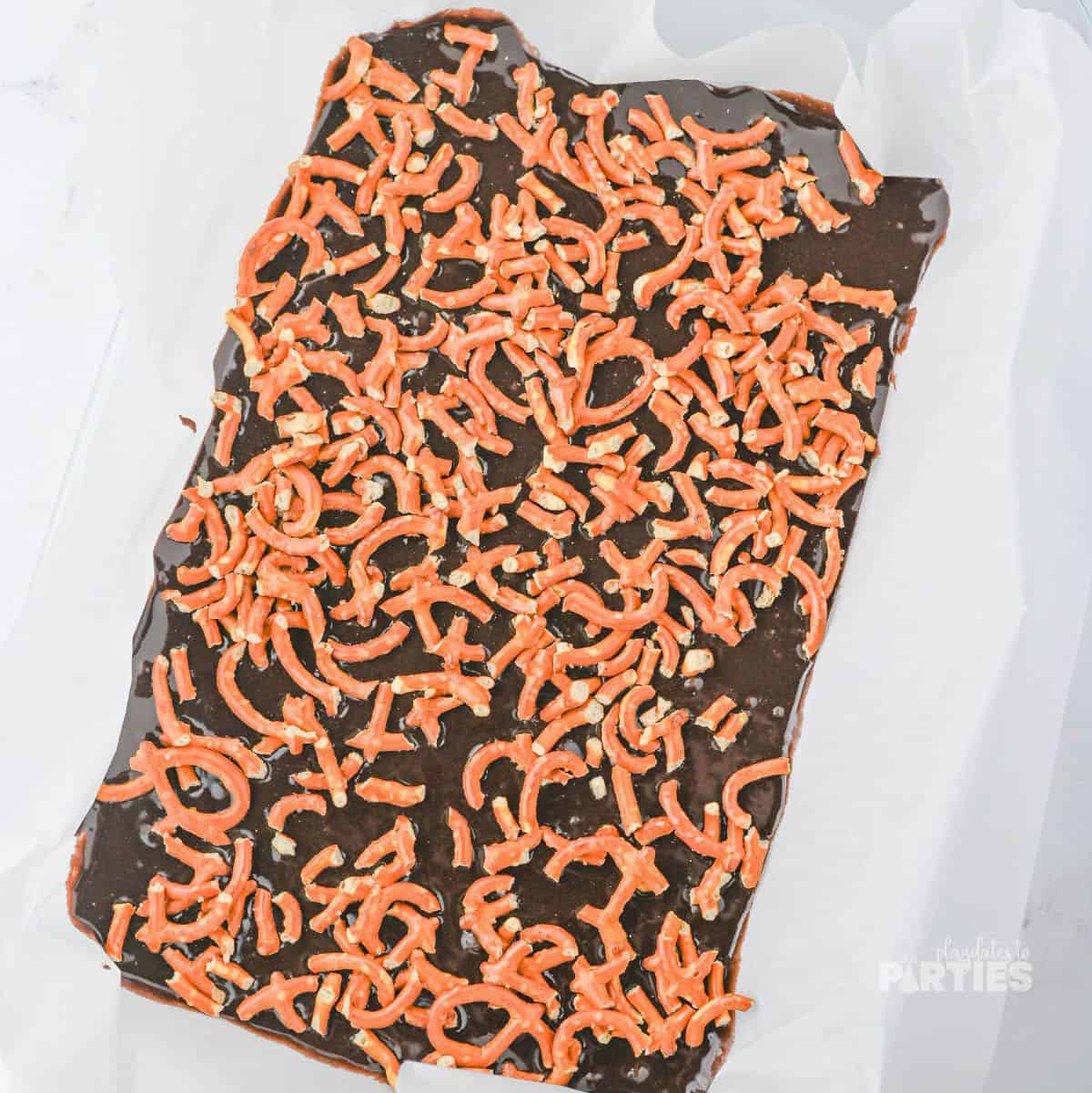 Brownie batter in a pan with crushed pretzels on top.