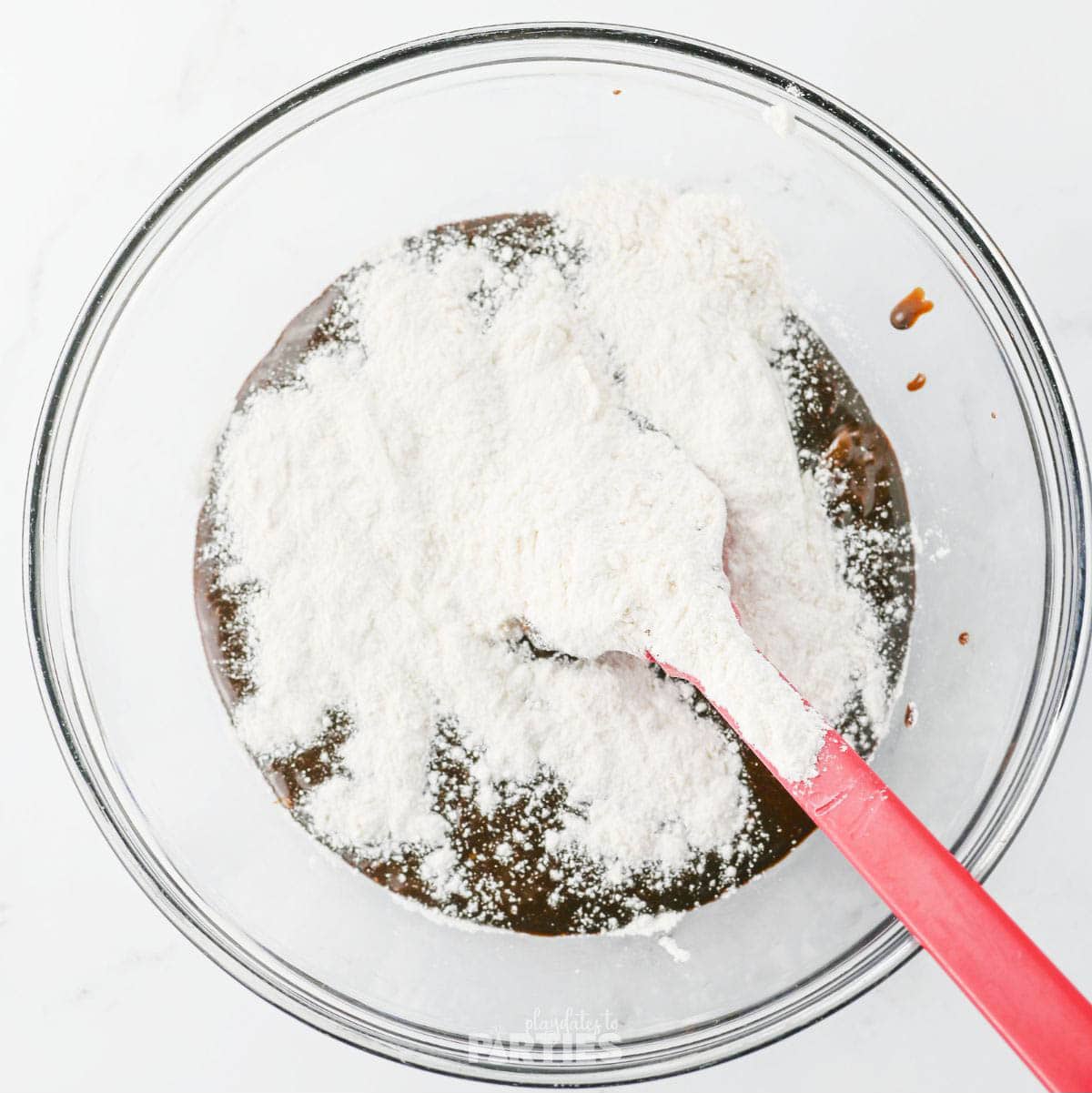 Combining dry ingredients with flour mixture to create brownie batter.