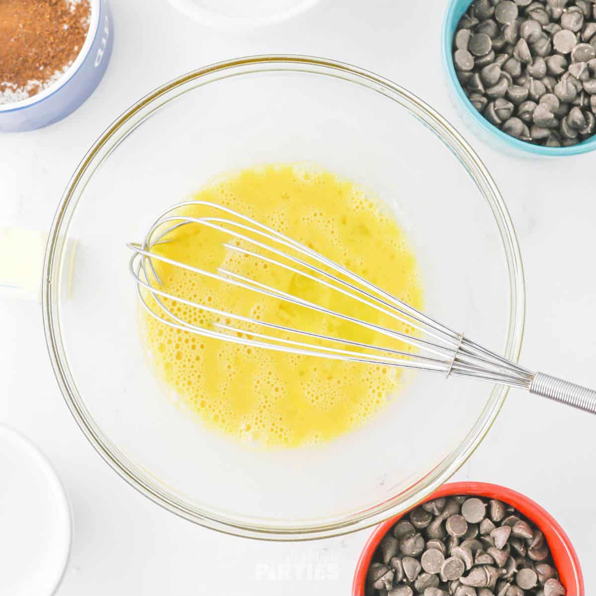 Whisking eggs and vanilla extract.