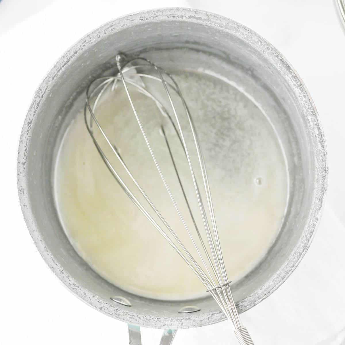 White sugar, butter, and water cooking in a saucepan.