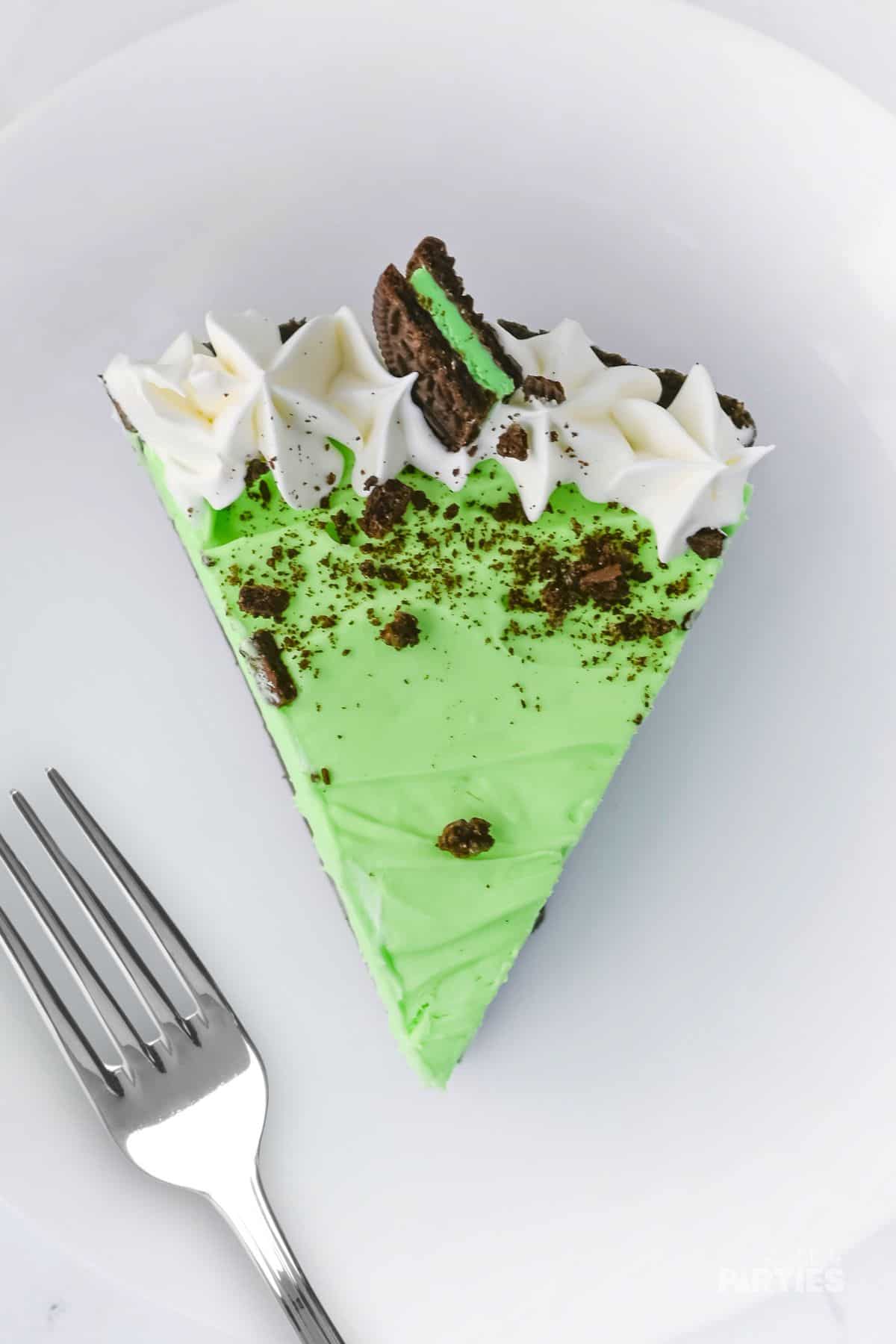 The top of the grasshopper pie features piped whipped cream, a mint Oreo cookie, and cookie crumbles.