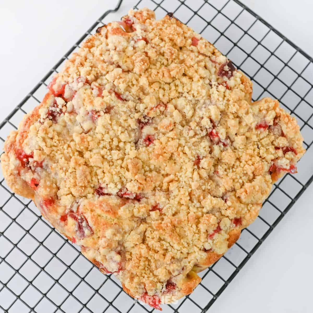 Freshly baked strawberry crumb cake on a cooling rack.