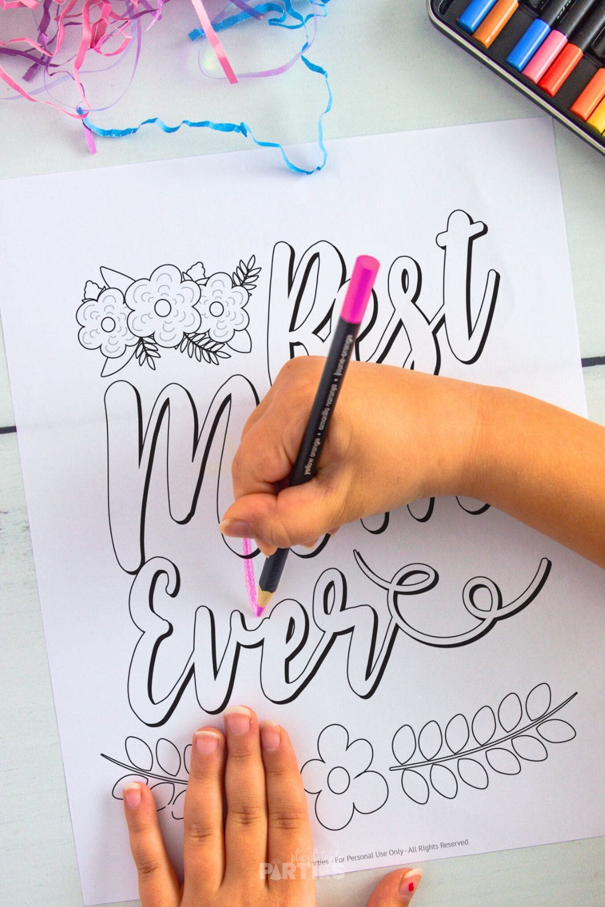A girl's hand coloring in a printout for Mom.