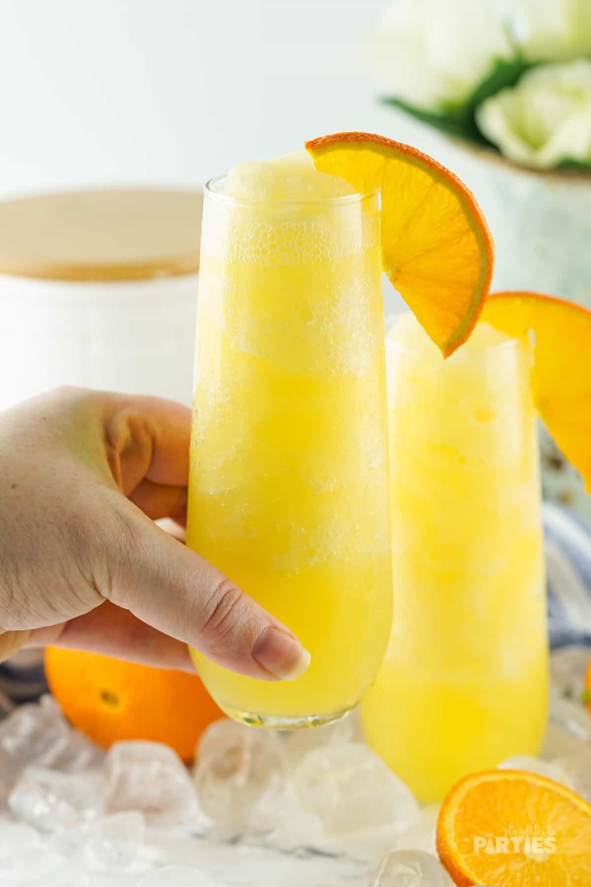A woman's hand holding a frozen orange cocktail.
