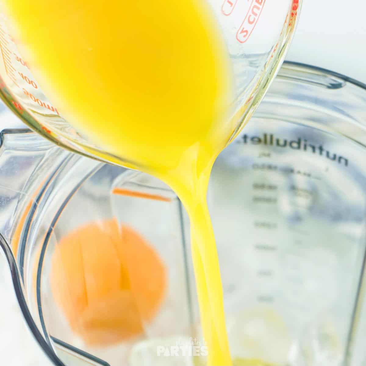 Pouring orange juice into a blender.