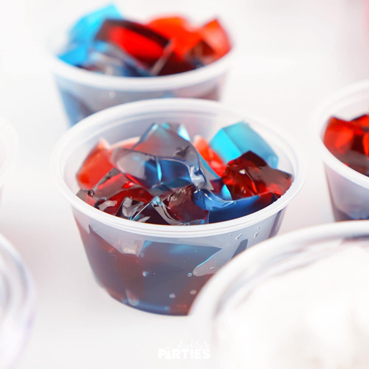2 ounce cups filled with pieces of red and blue jello.