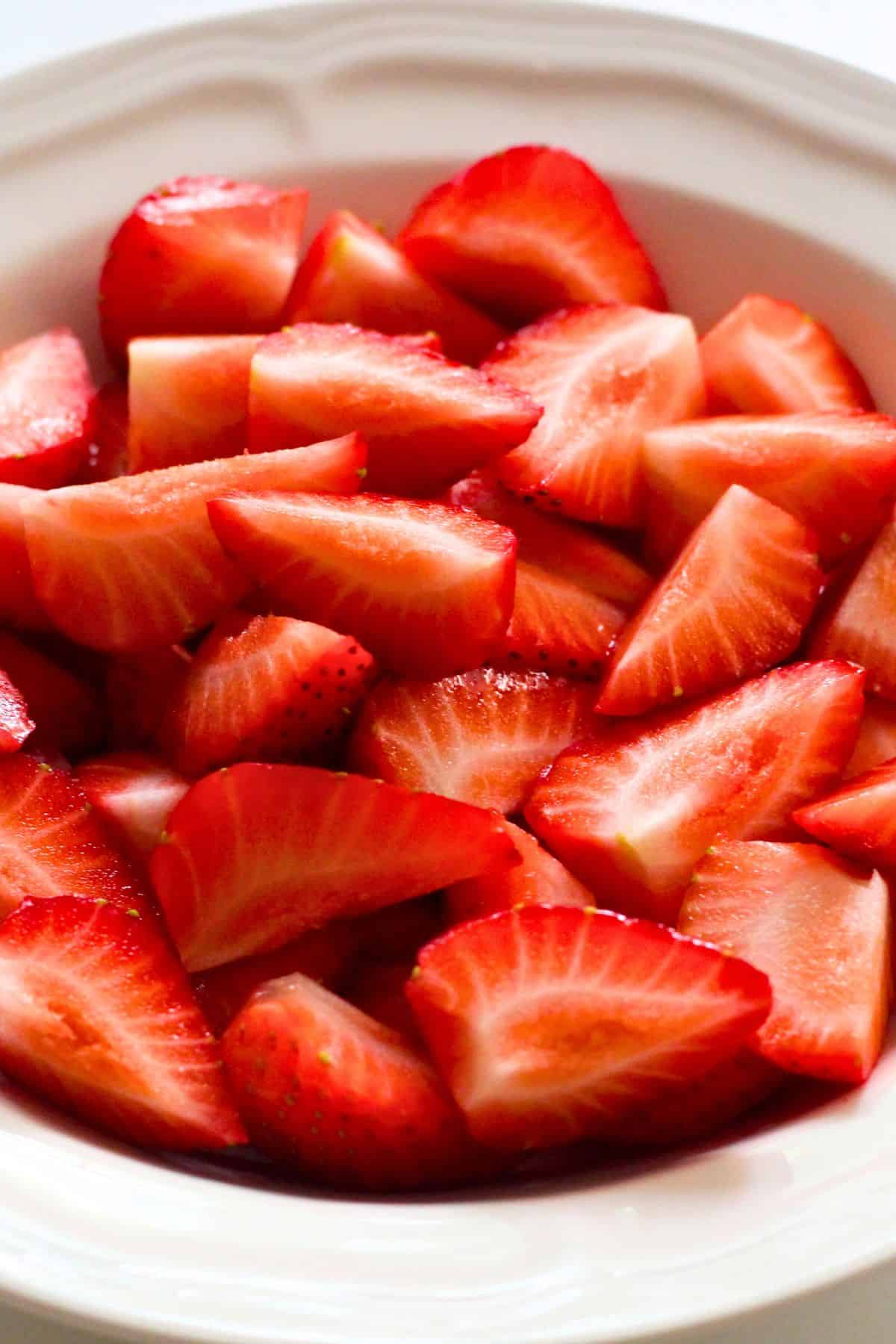 A bowl of strawberries cut into quarters.