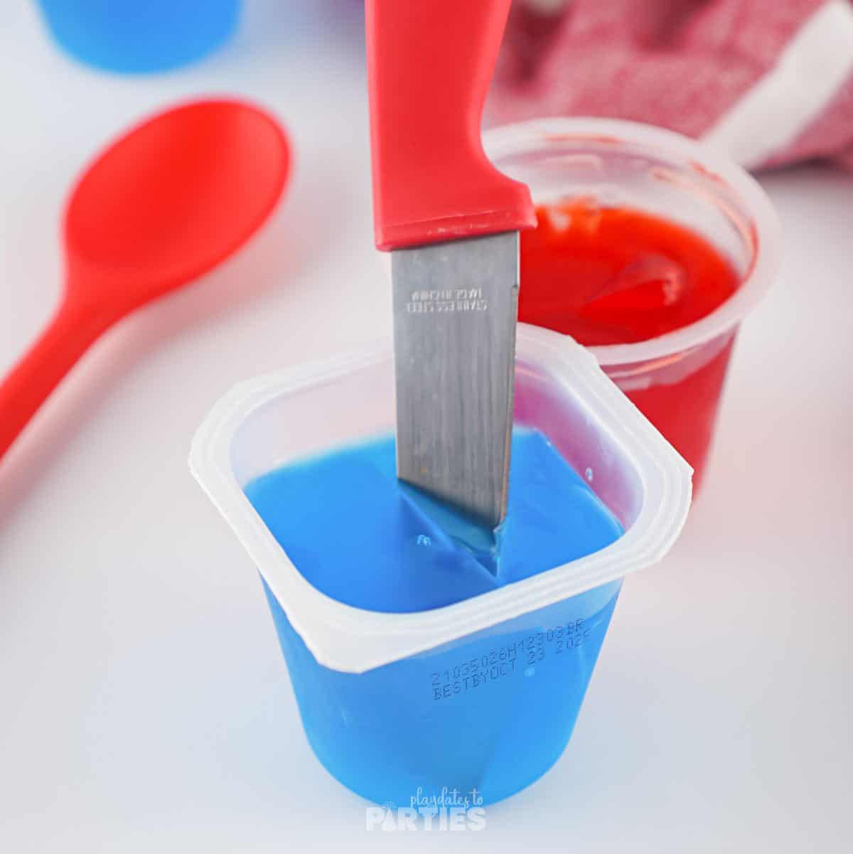 A knife stuck in a cup of blue jello.
