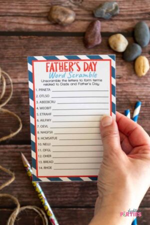 A woman's hand holding a Father's Day Word Scramble card.