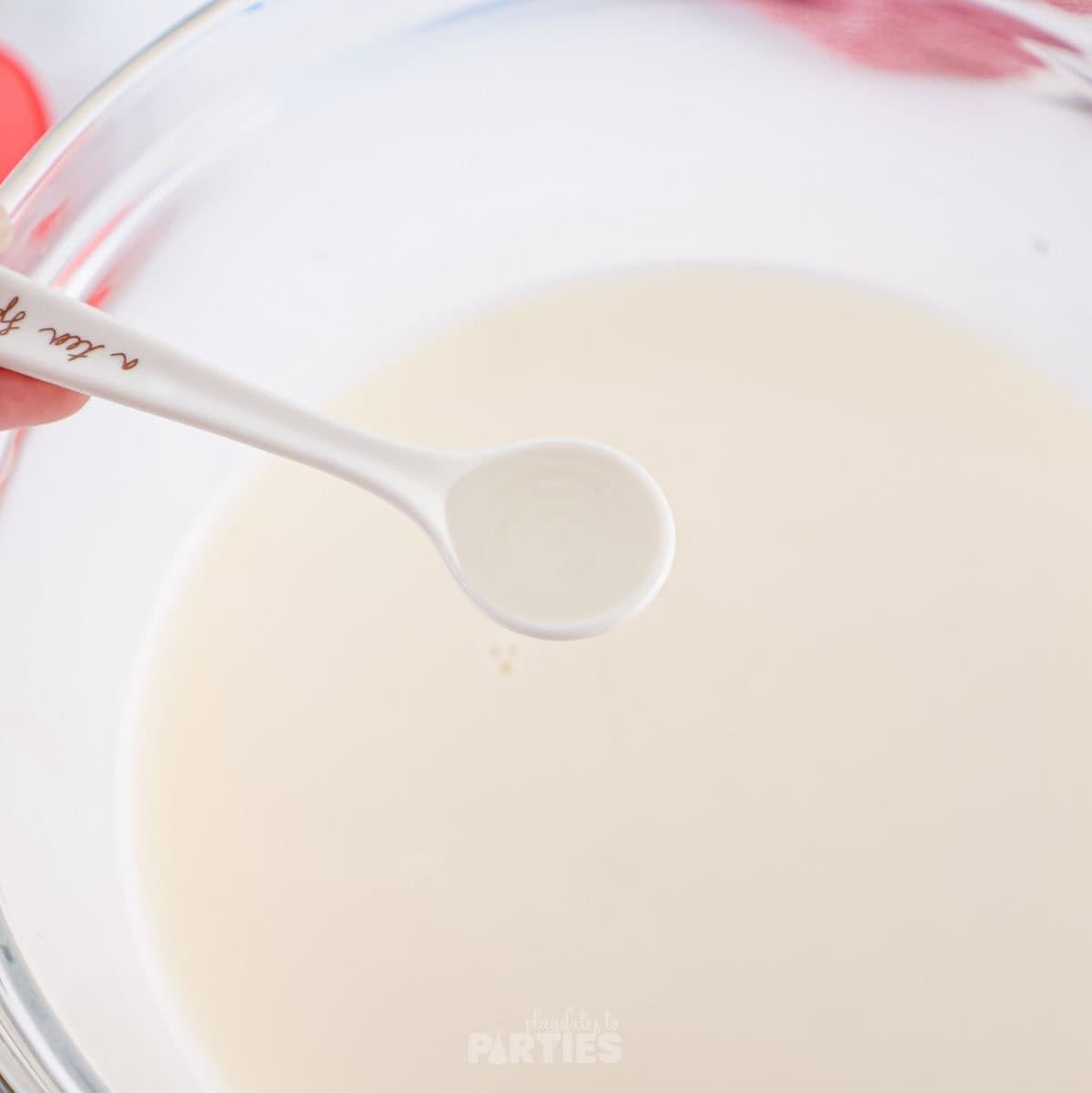 Adding flavored extract to a bowl with sweetened condensed milk.