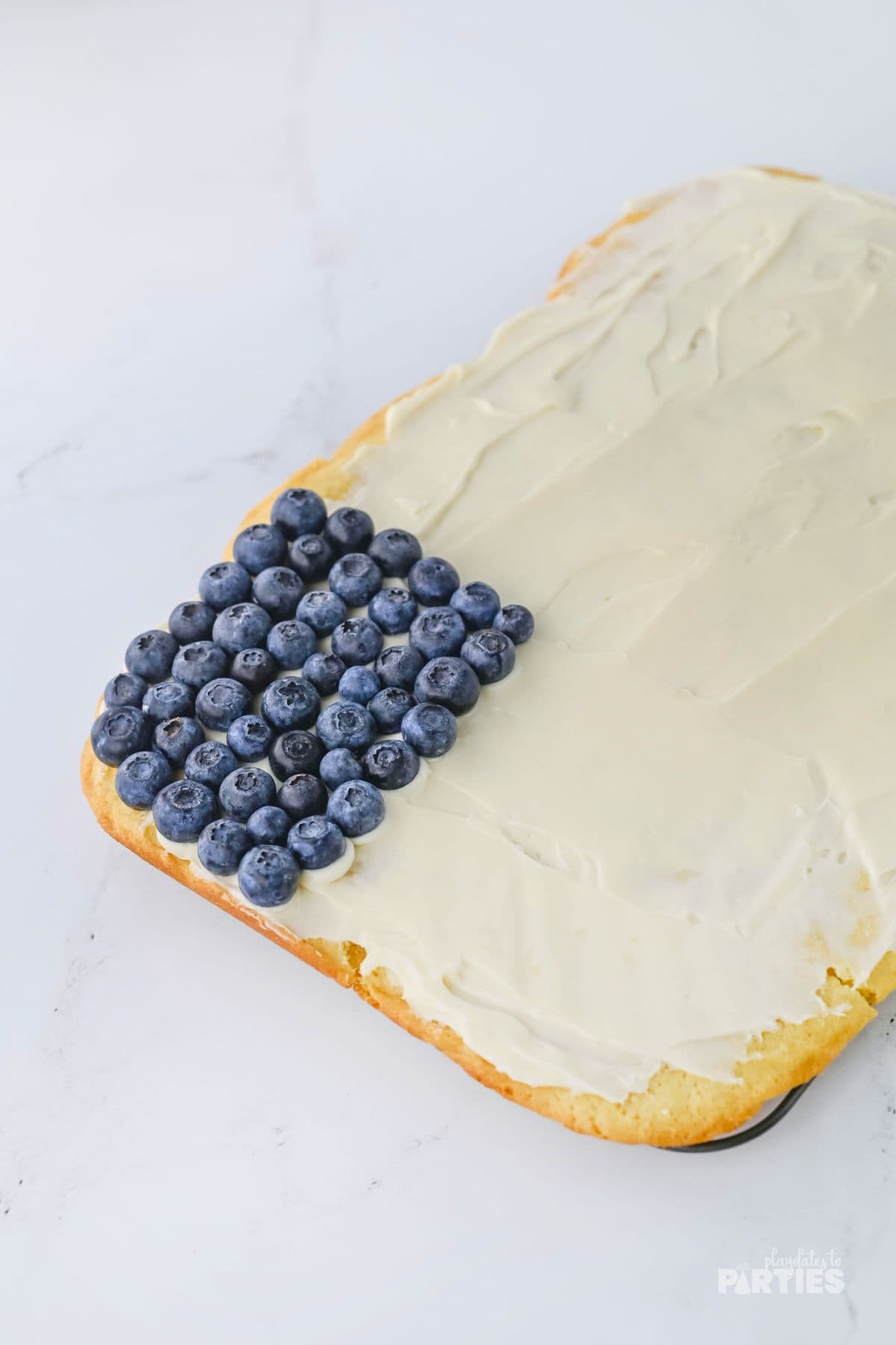 Blueberries arranged in a corner of a sugar cookie fruit pizza.