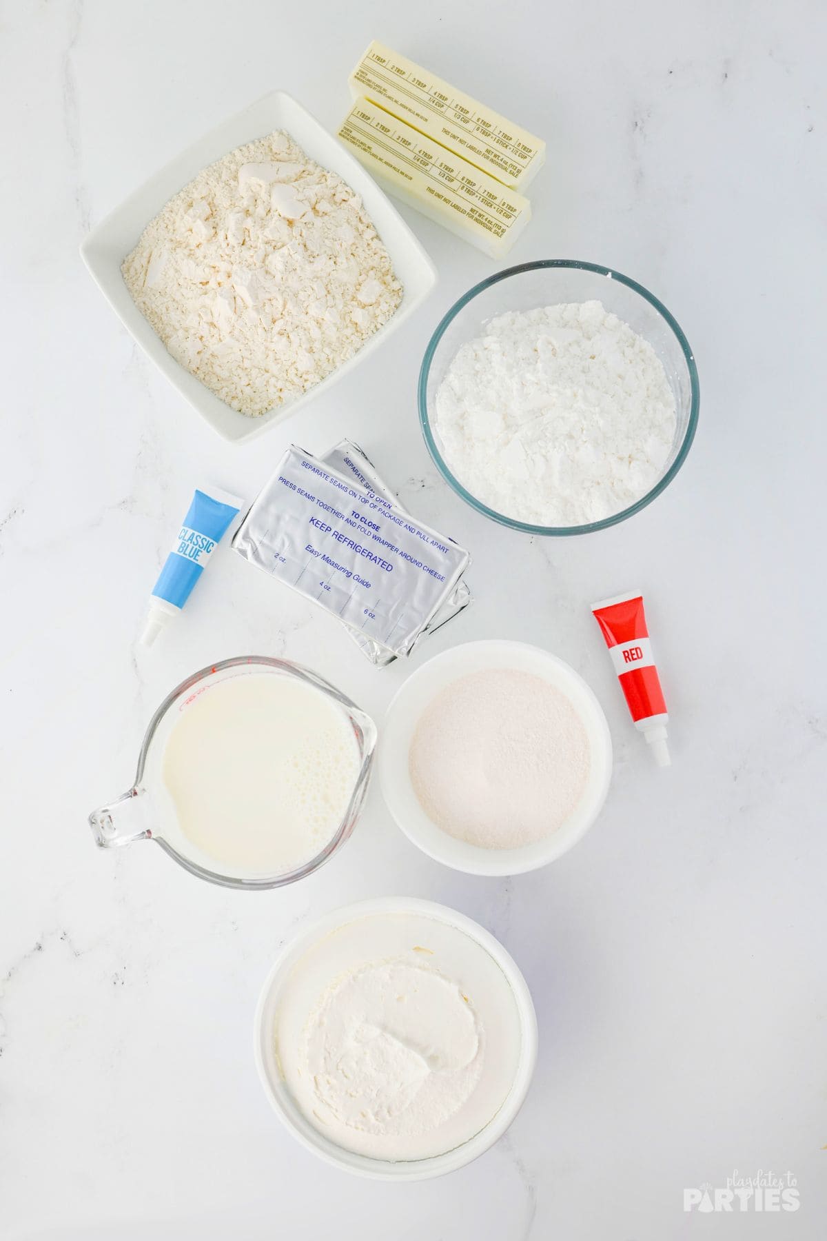 Ingredients for patriotic layered cheesecake on a marble surface.