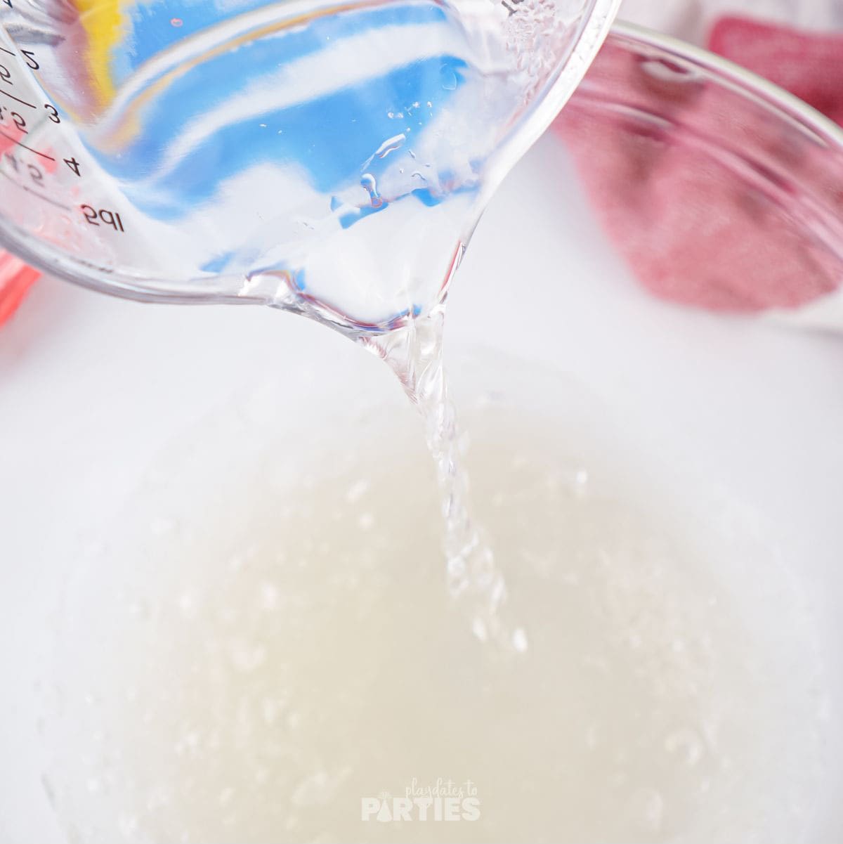 Pouring hot water into a bowl of bloomed gelatin.