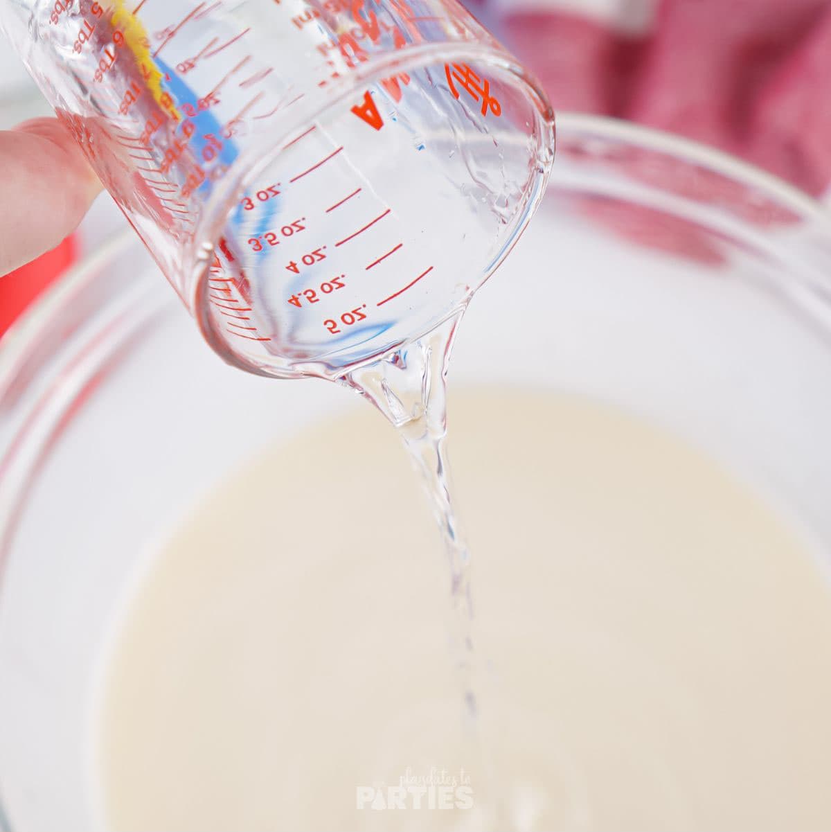 Pouring water into a bowl with sweetened condensed milk.