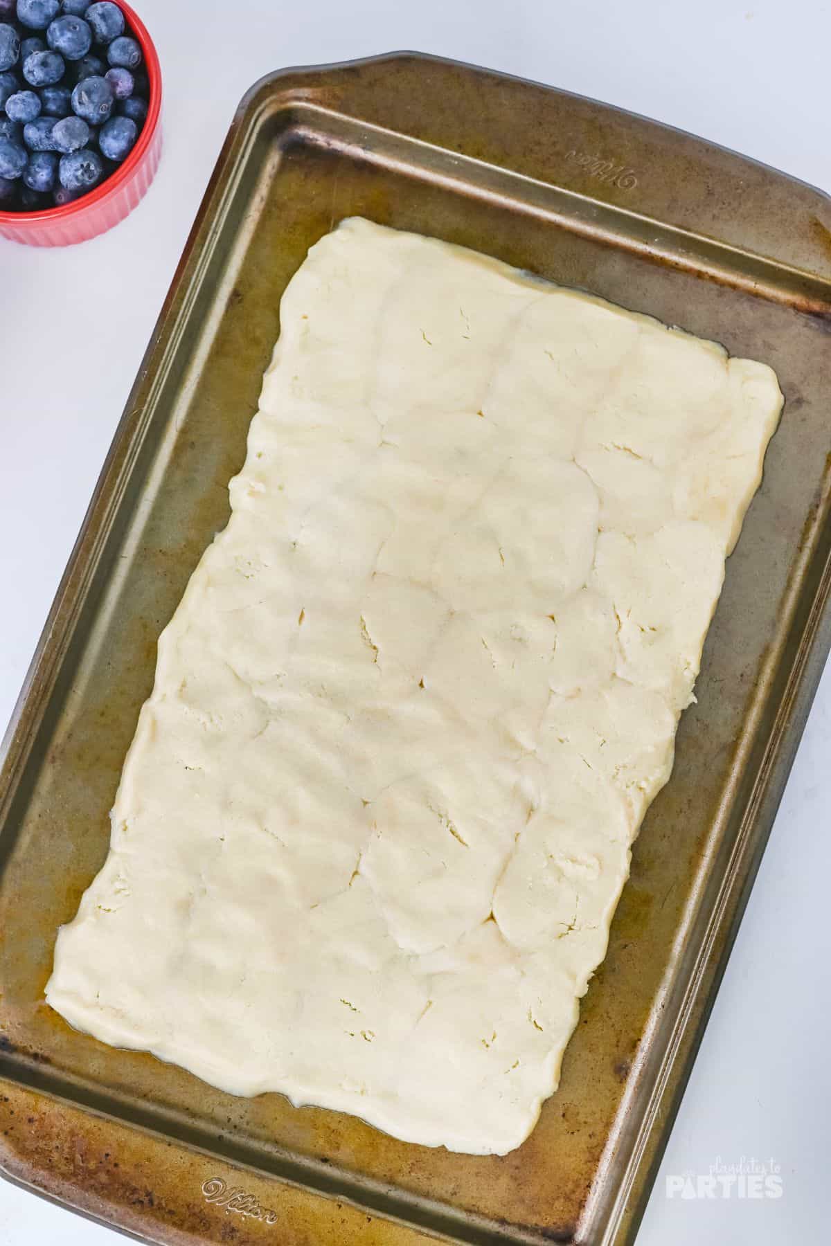 Sugar cookie dough shaped as a rectangle on a cookie sheet.