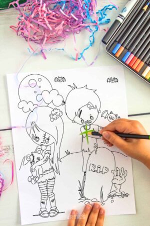 A girl's hand coloring in a page for Halloween.