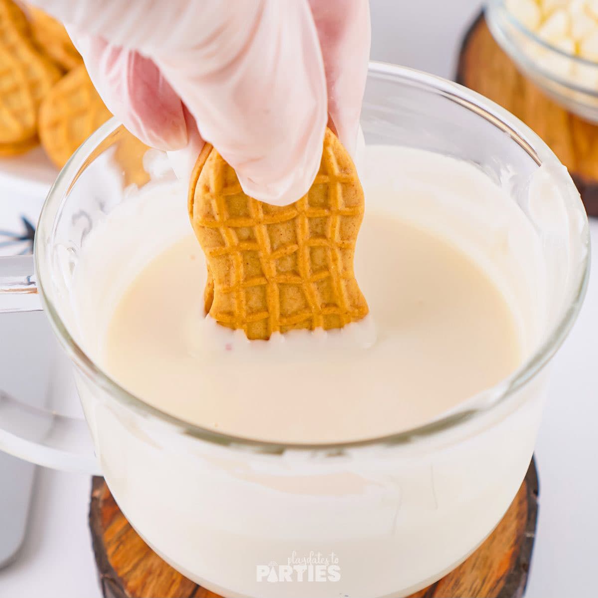 Dipping a cookie into melted white chocolate.