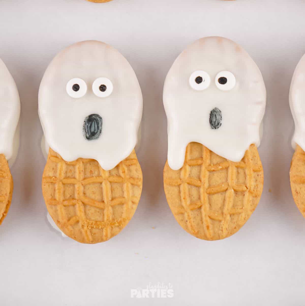 Ghost cookies with candy eyes and mouths drawn on.
