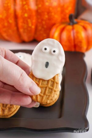 A woman's hand holding a Nutter Butter ghost cookie.