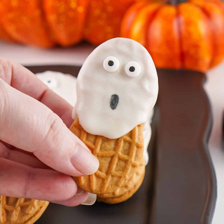 A woman's hand holding a Nutter Butter ghost cookie.