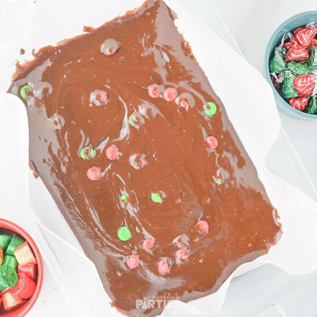Brownie mix spread in a cake pan with candies mixed in.