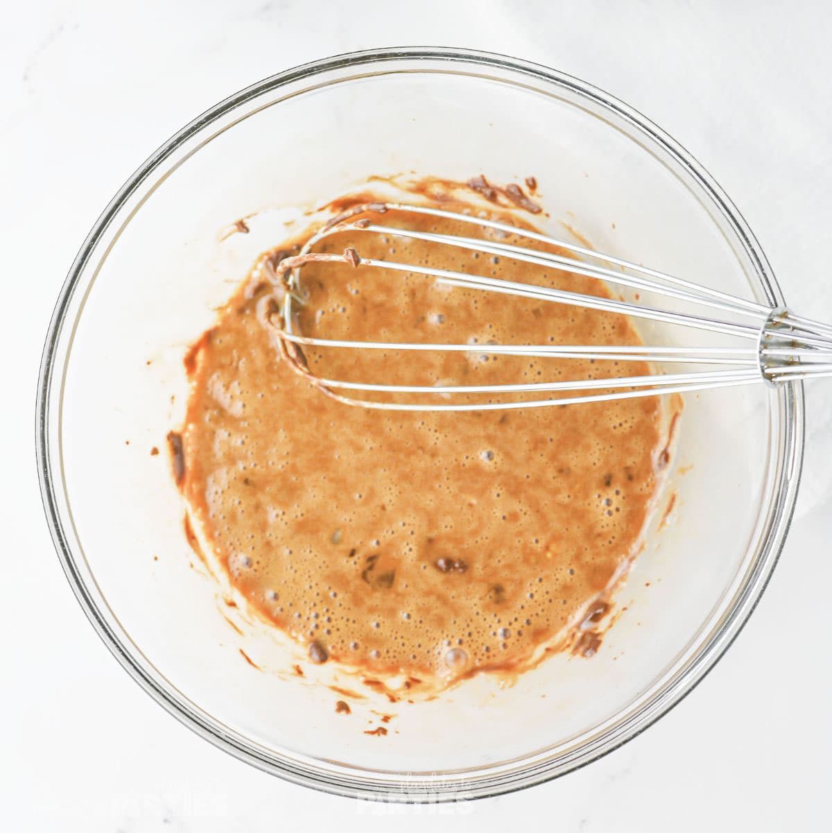 Whisking together melted butter, sugars, and, vanilla.